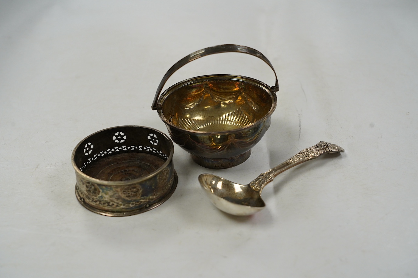 A George III silver small epergne basket, London, 1800, diameter 80mm, a large William IV silver caddy spoon and an Old Sheffield plate sauce bottle coaster. Condition - fair